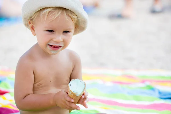 Édes szőke kisgyermek fiú, eaiting fagylaltot a strandon — Stock Fotó