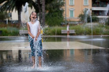Su splashi ile bir jet çeşmeler üzerinde oynayan sevimli okul öncesi çocuk