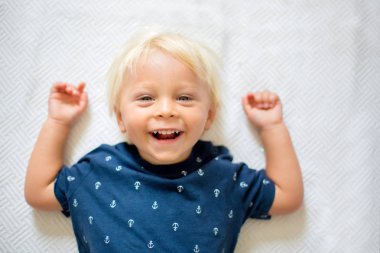 Çocuk, beyaz battaniye üzerinde yerde yatan, ca bakarak