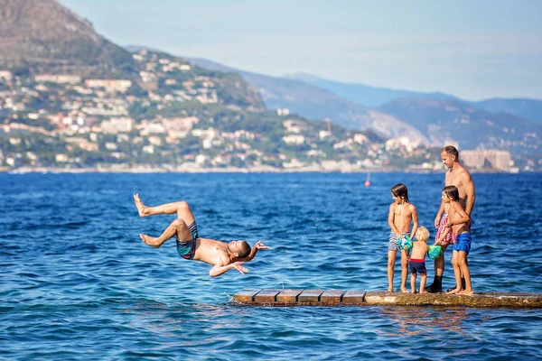 Heureux groupe de personnes, enfants et adultes, sautant dans l'eau — Photo