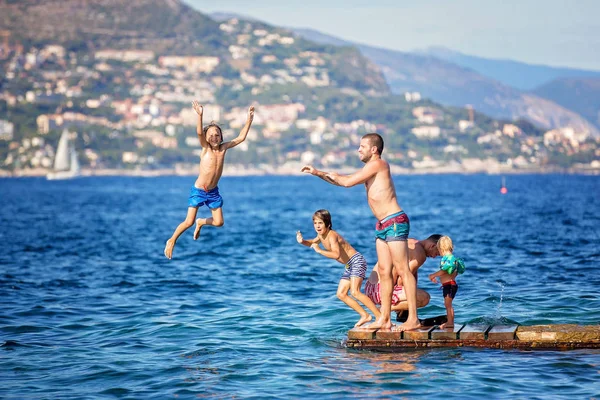 Heureux groupe de personnes, enfants et adultes, sautant dans l'eau — Photo