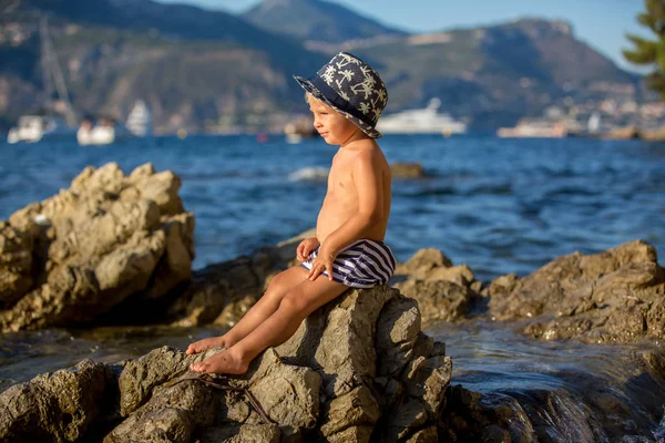 Dolce bambino ragazzo con cappello estivo e occhiali da sole, seduto sul — Foto Stock