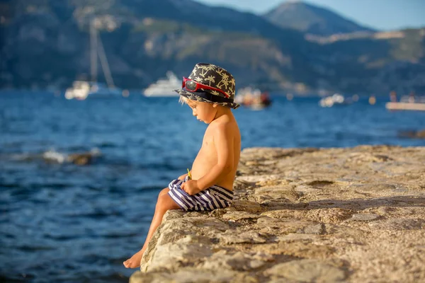 Dulce niño con sombrero de verano y gafas de sol, sentado en el — Foto de Stock