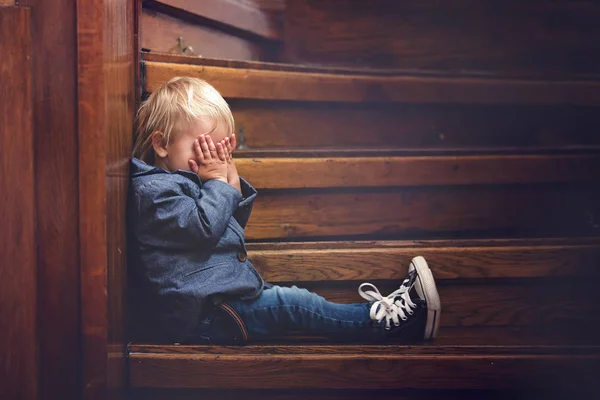 Ledsen barn, sitter på en trappa i ett stort hus, koncept för Bu — Stockfoto