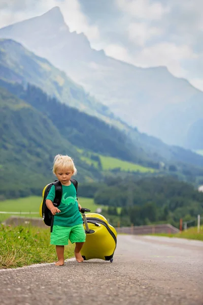 Bambino piccolo, ragazzo con zaini e valigia, viaggia sulla roa — Foto Stock