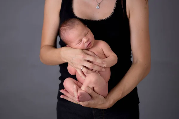 Mother kissing and hugging newborn son at gray background, tende — Stock Photo, Image
