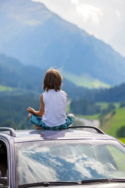 Niño lindo, niño sentado en el techo de un coche, meditando disfrutando de th —  Fotos de Stock