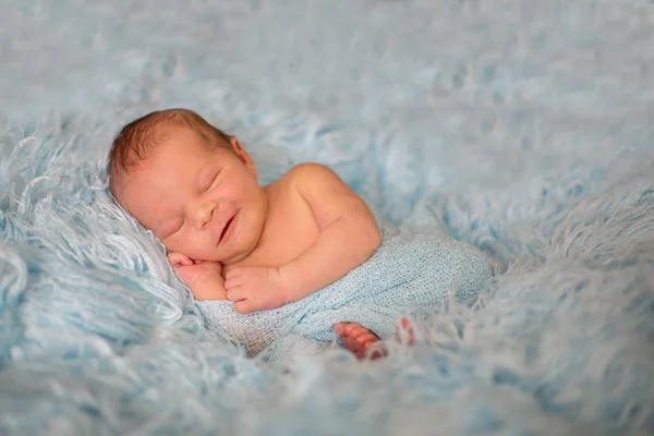 Щаслива усміхнена новонароджена дитина в обгортці, що щасливо спить у затишному хутрі — стокове фото