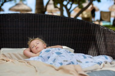 Sevimli sarışın yürümeye başlayan çocuk, t büyük bir yuvarlak plaj sandalyede uyku