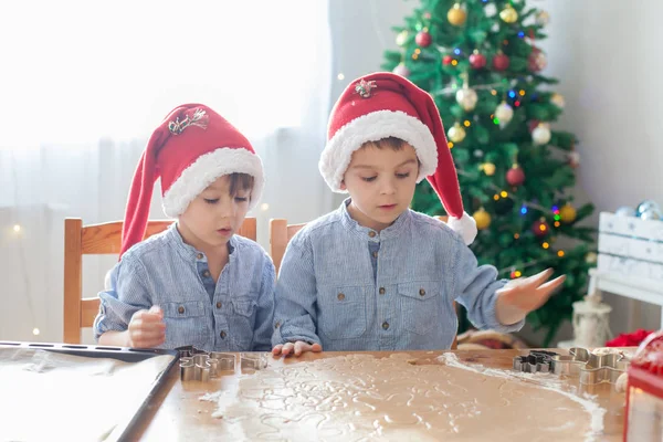 Dos chicos lindos con sombrero de santa, preparando galletas en casa, Christm — Foto de Stock