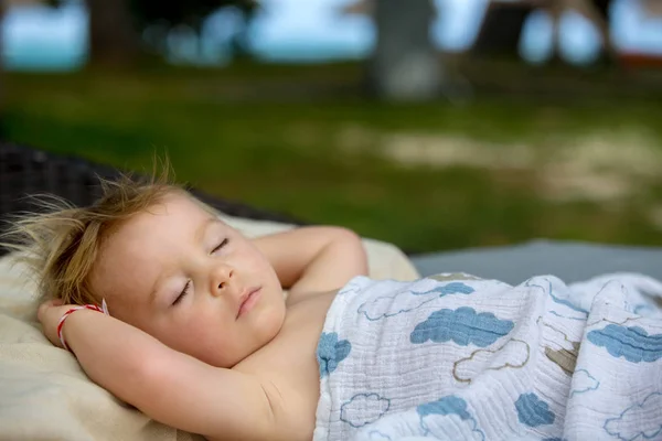 Cute blond chłopiec maluch, spanie na dużym okrągłym fotelu na plaży t — Zdjęcie stockowe