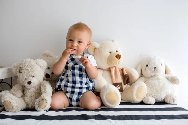 Sød baby dreng, lille barn, der leger hjemme med masser af legetøj - Stock-foto