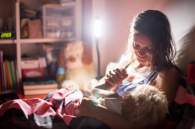Anne, geceleri evde onun bebek çocuk için bir kitap okuma, nigh
