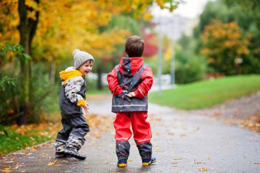 İki çocuk, yağmurlu bir günde oyuncak parkta kavga