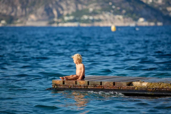 Ragazzino, bambino, seduto sul molo nel mare, godendo della vista — Foto Stock