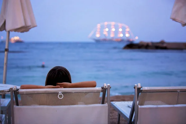 Kinderen, zittend op het strand, kijken verlicht schip in de Oceaan — Stockfoto