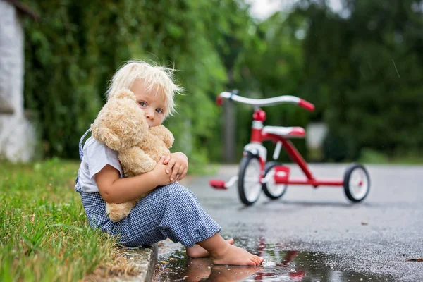 Carino bambino, con orsacchiotto giocattolo, seduto sulla strada in t — Foto Stock