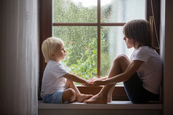 Glückliche Geschwister, junge Brüder, sitzen auf einem Fensterschild auf einem ra — Stockfoto