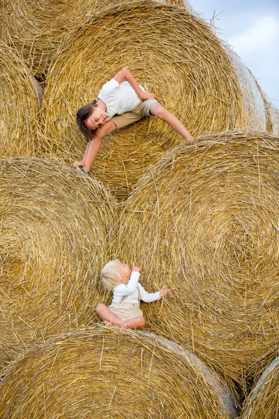 Niños felices, jugando en pajar verano —  Fotos de Stock