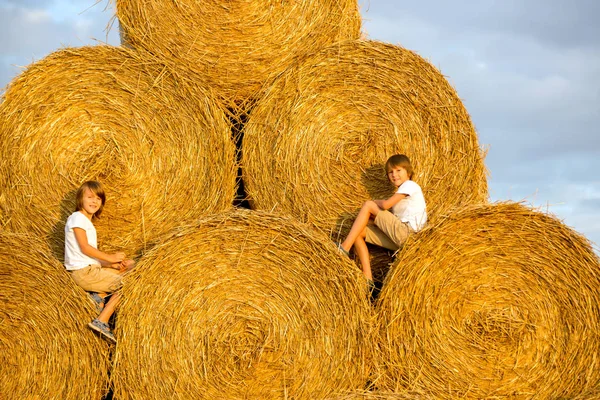 Happy children, playing on haystacks summertime — Stock Photo, Image