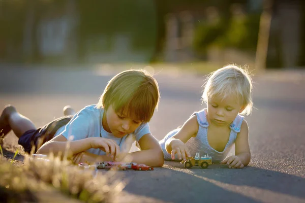 Hermosos niños, hermanos, jugando con juguetes de coche en el sol — Foto de Stock