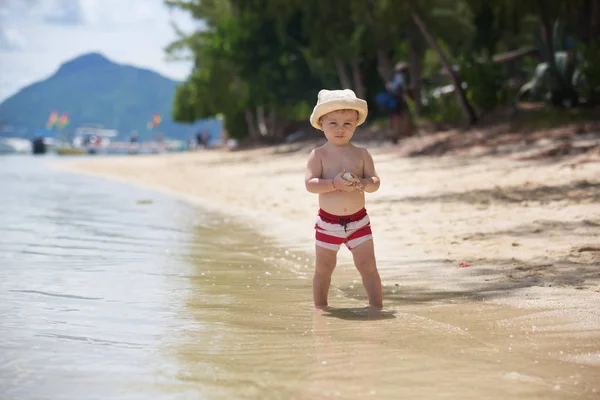 Petit garçon doux, jouant en eau peu profonde sur une plage tropicale — Photo