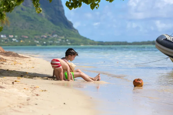 Słodkie dziecko, siedzieć na brzegu na plaży z kokosa, cieszącymi — Zdjęcie stockowe