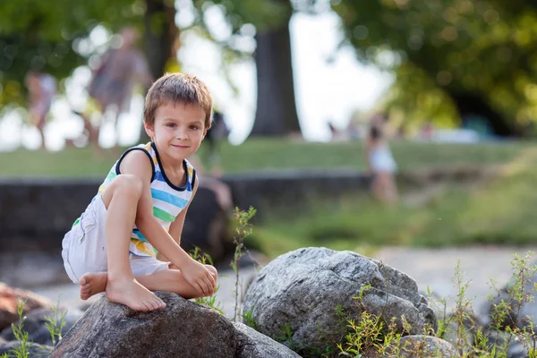 Bambino carino, ragazzo, seduto su una costa del lago, ritratto serale — Foto Stock