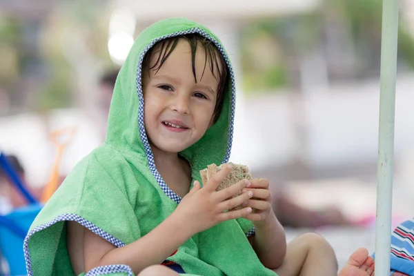 Leuke jongen, broodje eten op het strand — Stockfoto