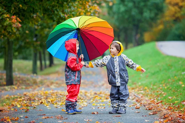 Umbrel ile parkta oynayan iki sevimli çocuk, erkek kardeşler, — Stok fotoğraf