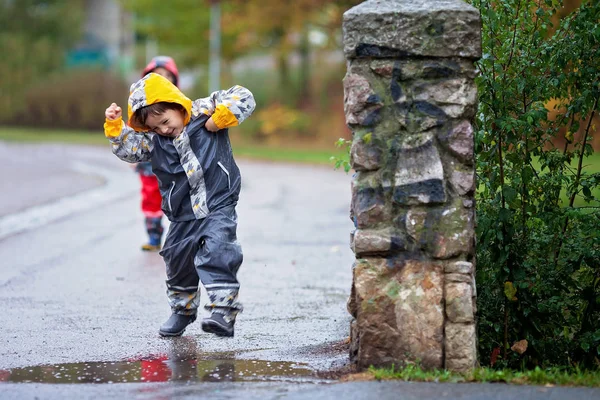 Rapaz bonito no parque, brincando na chuva, pulando em poças — Fotografia de Stock