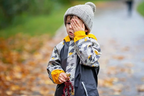 Lieve kind, jongen, spelen in het park op een regenachtige dag — Stockfoto