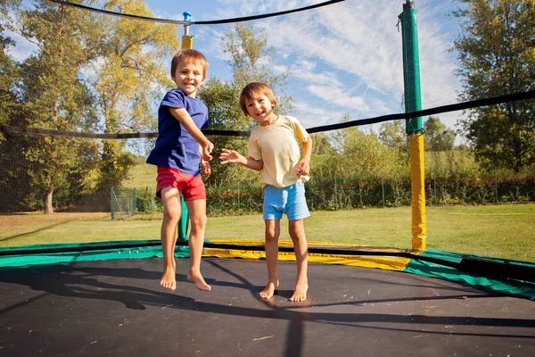 Two sweet kids, brothers, jumping on a trampoline, summertime, h — Stock Photo, Image