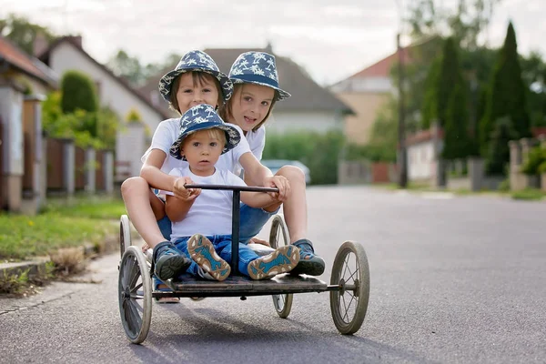 Anak-anak bahagia, anak laki-laki, naik mobil retro tua dengan empat roda — Stok Foto