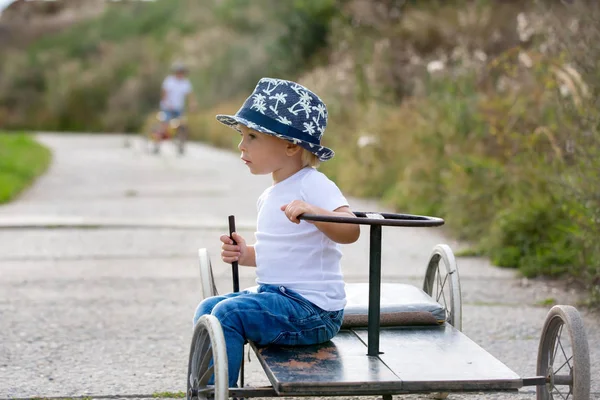 Adorable niño pequeño, montar viejo coche retro con cuatro ruedas — Foto de Stock