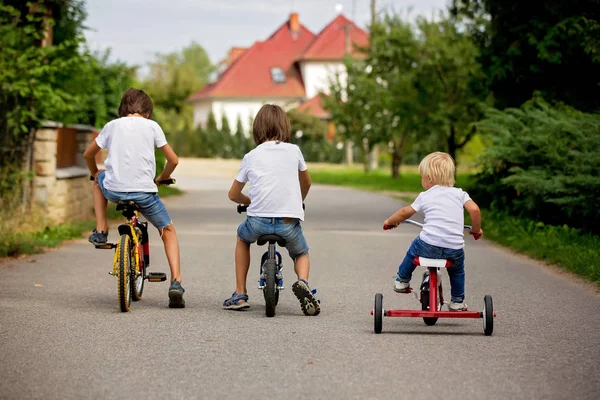 Három gyermek, lovas kerékpár, tricikli és a Balance Bike a St — Stock Fotó