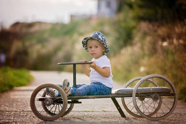 Uroczy chłopiec maluch, jazda stary samochód retro z czterema kołami — Zdjęcie stockowe
