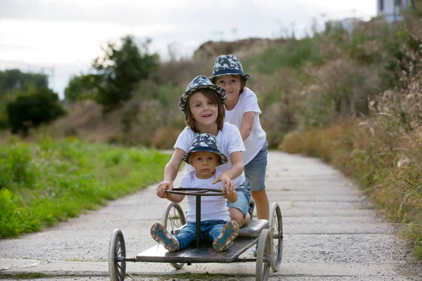 Счастливые дети, мальчики, катающиеся на старом ретро-автомобиле на четырех колесах — стоковое фото