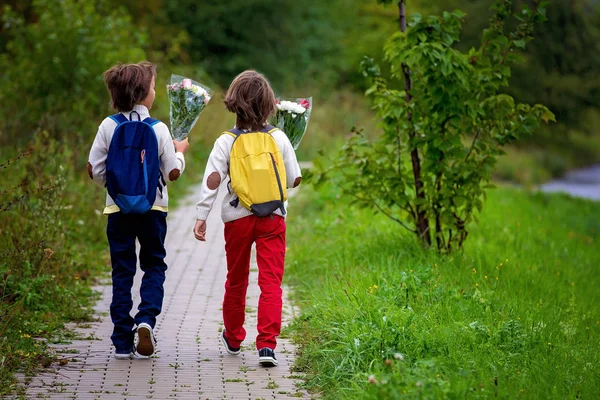 Heureux écoliers, tenant un bouquet de fleurs, allant à l'école — Photo