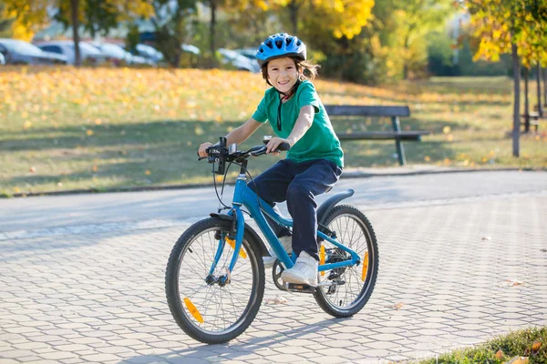 Fröhlicher Junge, der sich im Herbstpark mit dem Fahrrad vergnügt — Stockfoto