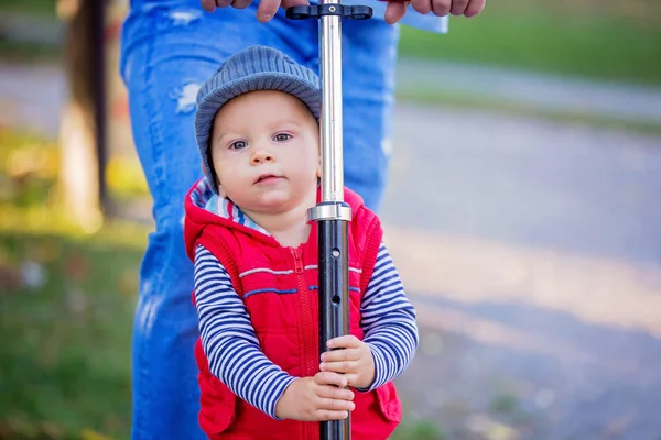 Father riding with his toddler son  scooter in a autumn park. . — Stock Photo, Image