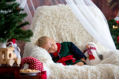 Baby boy, cute child, wearing santa claus robe sitting in rockin clipart