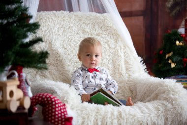 Sevimli çocuk noel t altında sandalyede oturan kitap okuma