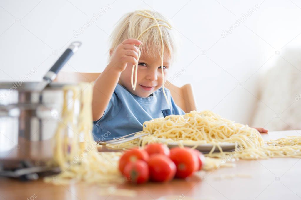 Little baby boy, toddler child, eating spaghetti for lunch and m