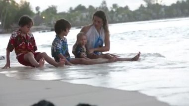 Mutlu güzel moda ailesi, çocuklar, Hawaii gömlekleri giyip gün batımında sahilde birlikte oynuyorlar, ailelerin neşeli tatili.
