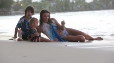 Mutlu güzel moda ailesi, çocuklar, Hawaii gömlekleri giyip gün batımında sahilde birlikte oynuyorlar, ailelerin neşeli tatili.