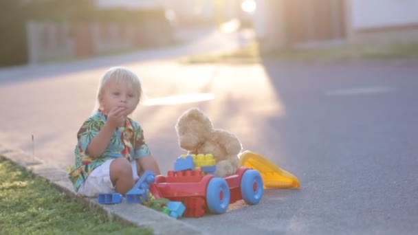 美しい幼児の子供 プラスチック製のおもちゃ ブロック 小さな村の日没の車で遊ぶ — ストック動画