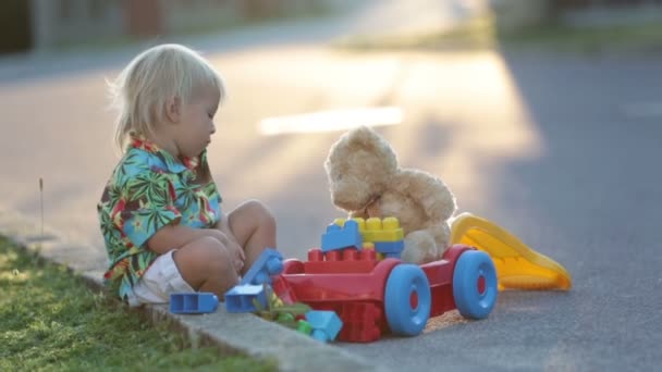 Όμορφο Μικρό Παιδί Παίζει Πλαστικά Παιχνίδια Μπλοκ Αυτοκίνητα Στο Ηλιοβασίλεμα — Αρχείο Βίντεο