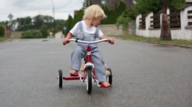 Sevimli küçük çocuk, oyuncak ayı oyuncak ile, yağmurda sokakta üç tekerlekli bisiklet sürme, barefeet, yaz