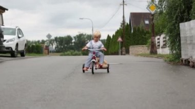 Sevimli küçük çocuk, oyuncak ayı oyuncak ile, yağmurda sokakta üç tekerlekli bisiklet sürme, barefeet, yaz